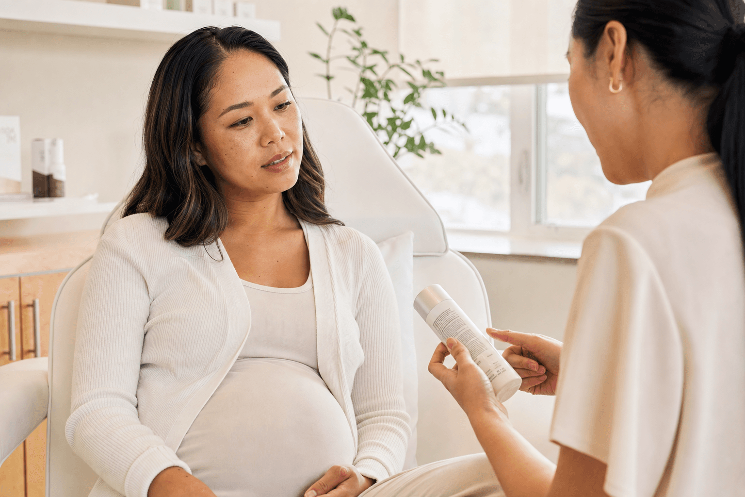 Pregnant woman reviewing a facial product label during a consultation