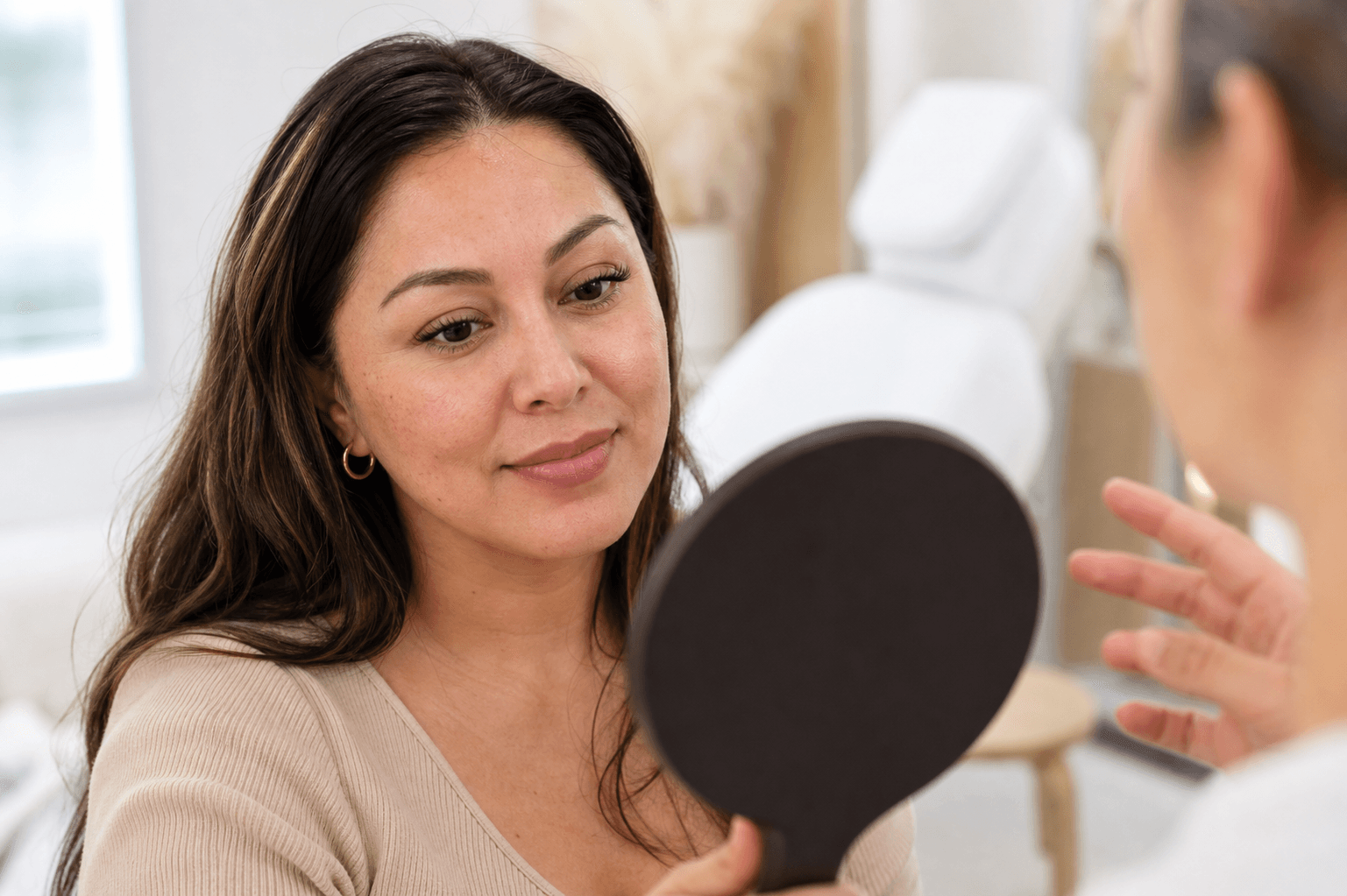 Woman reviewing her natural lashes in a mirror during a beauty consultation