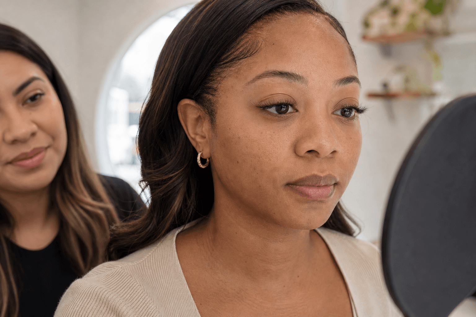 Woman checking grown-out eyelash extensions in a mirror during a consultation