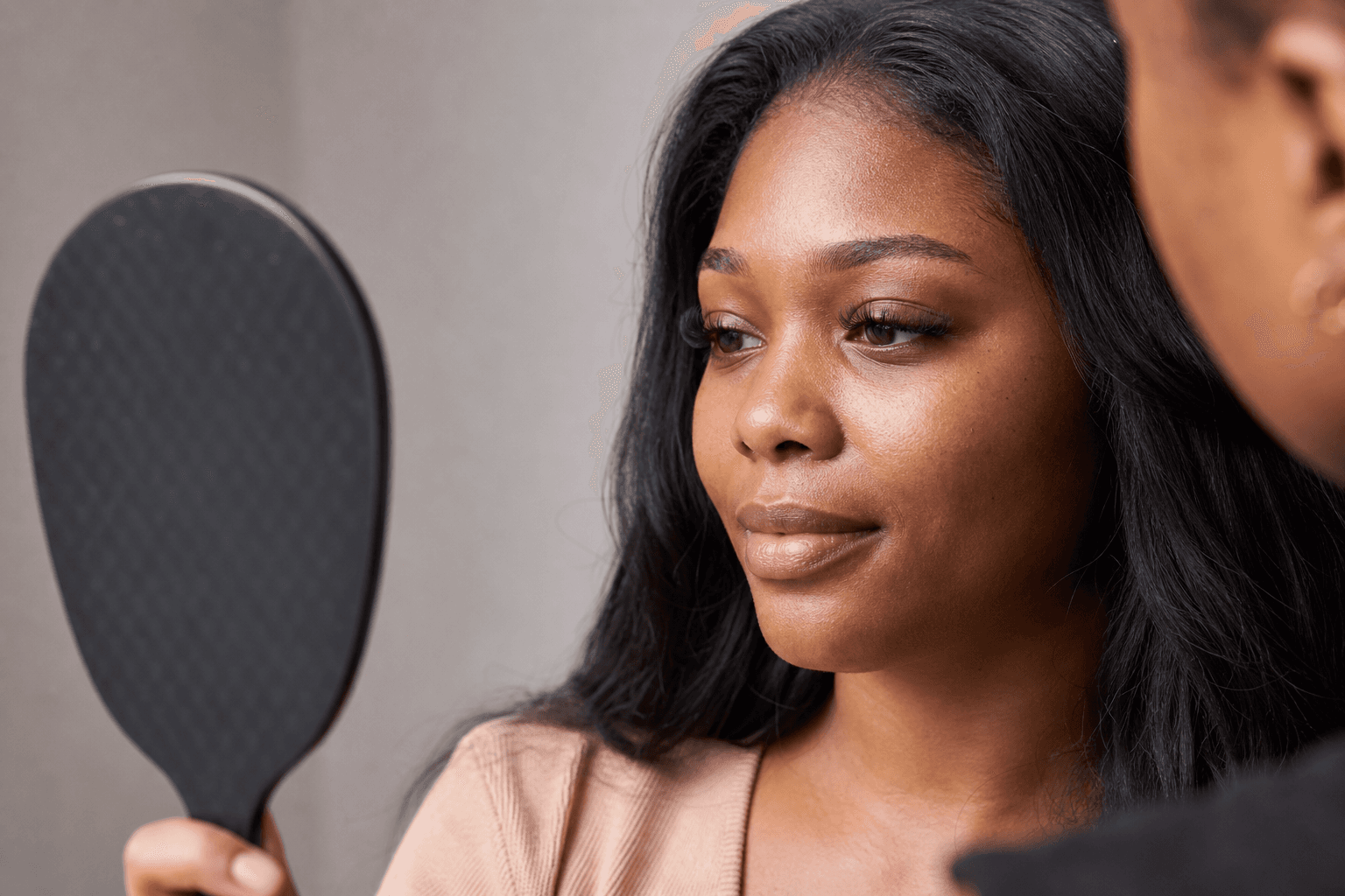 Woman reviewing a lightweight kitten-style eyelash set in a mirror during a consultation