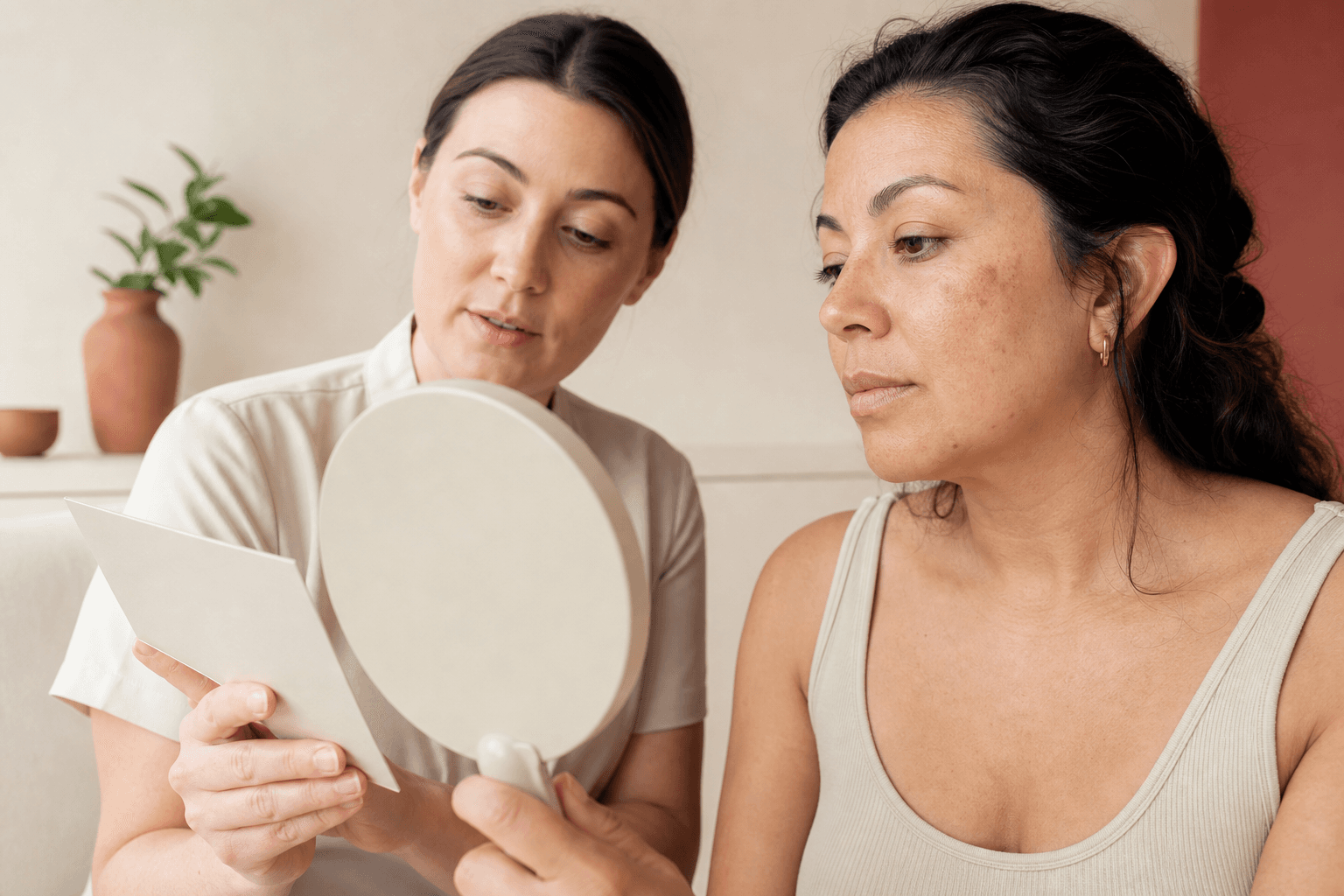 Woman reviewing subtle facial dark spots in a mirror during a skin consultation