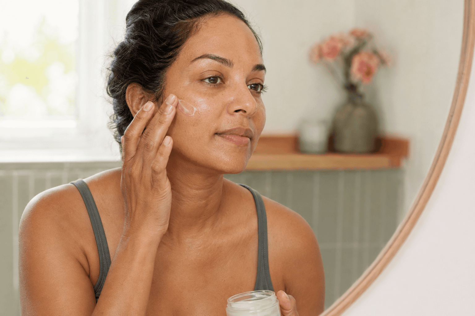 Woman applying moisturizer to naturally textured skin after a facial