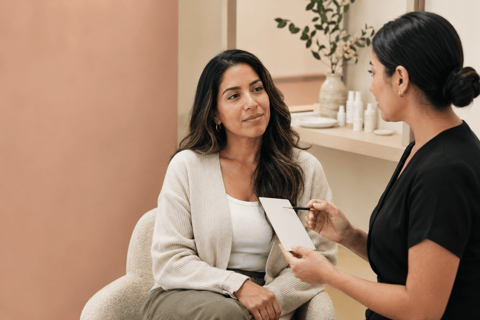 Client discussing facial options with an esthetician in a warm skincare studio