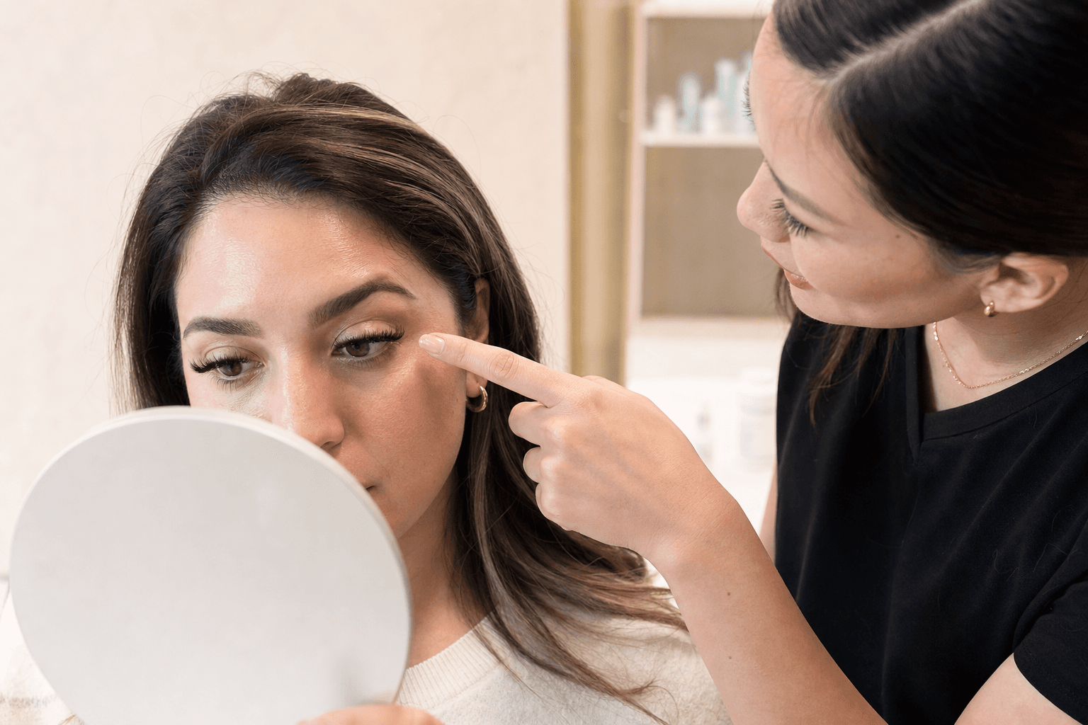 Client and lash professional examining eyelash extension retention in a handheld mirror
